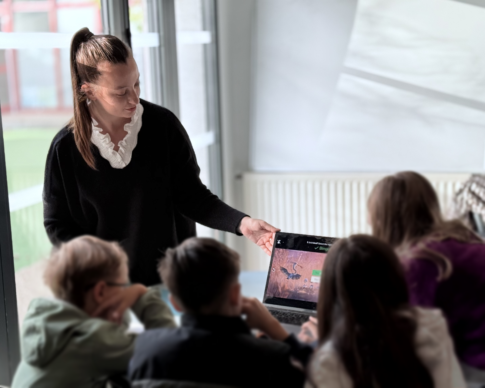 Kate aidant un enfant à utiliser une tablette pendant un cours d'anglais